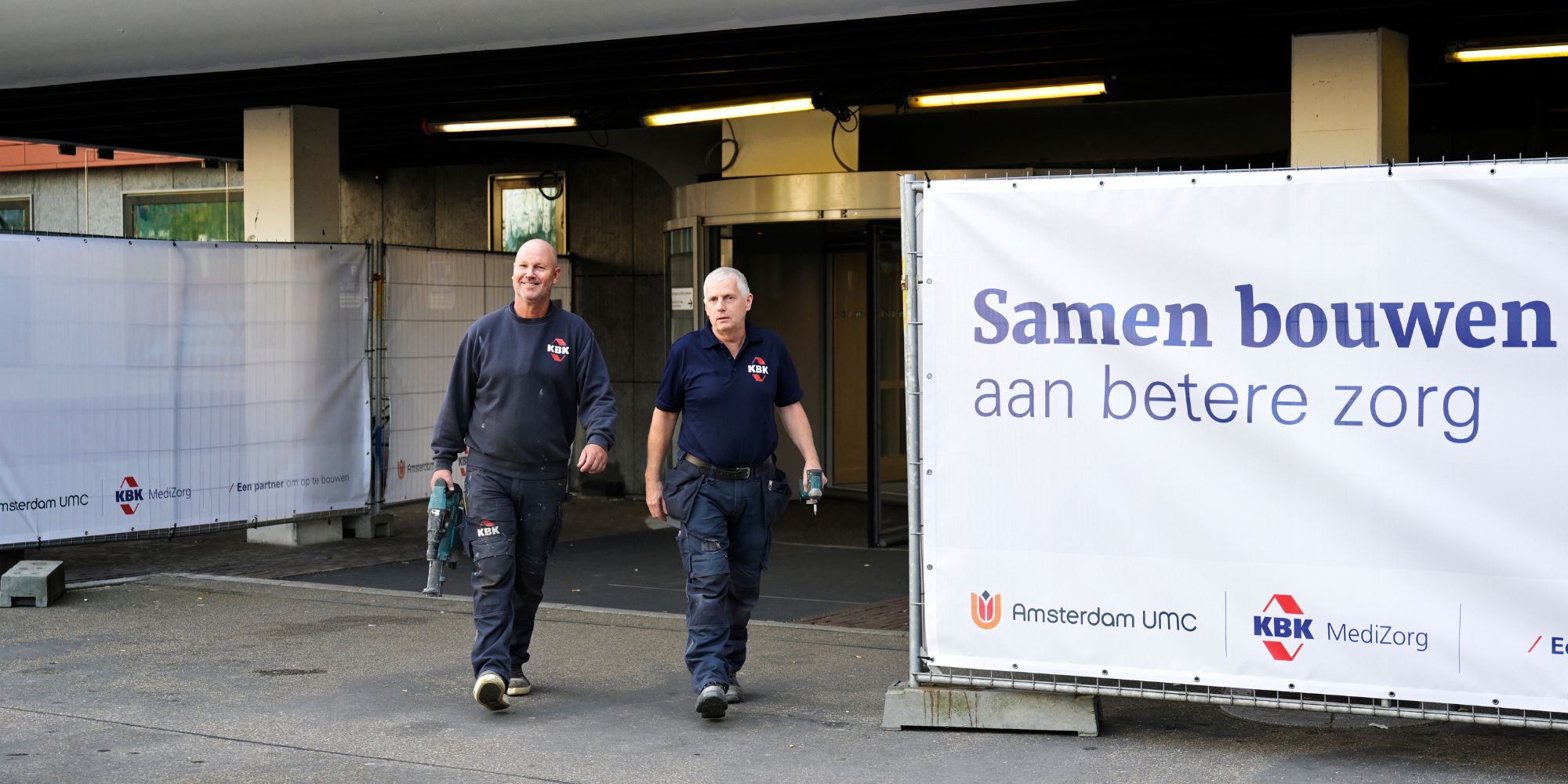 Vaklieden lopen bij ingang van ziekenhuis met gereedschap